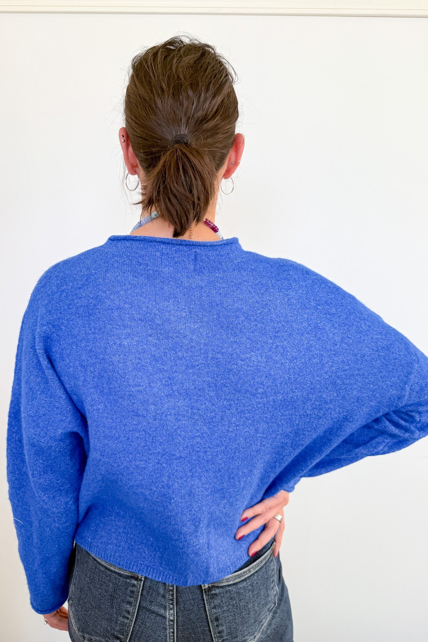 Person wearing a blue sweater from behind on a white background