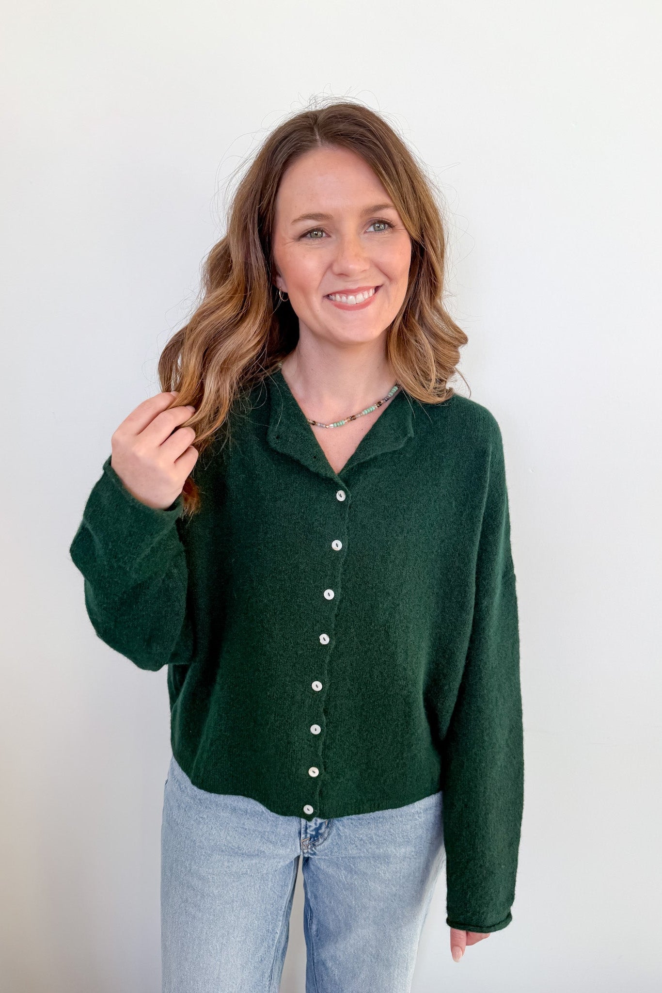 Woman wearing a green sweater with a white background