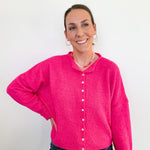 Woman wearing a bright pink cardigan against a white background