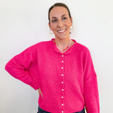 Woman wearing a bright pink cardigan against a white background