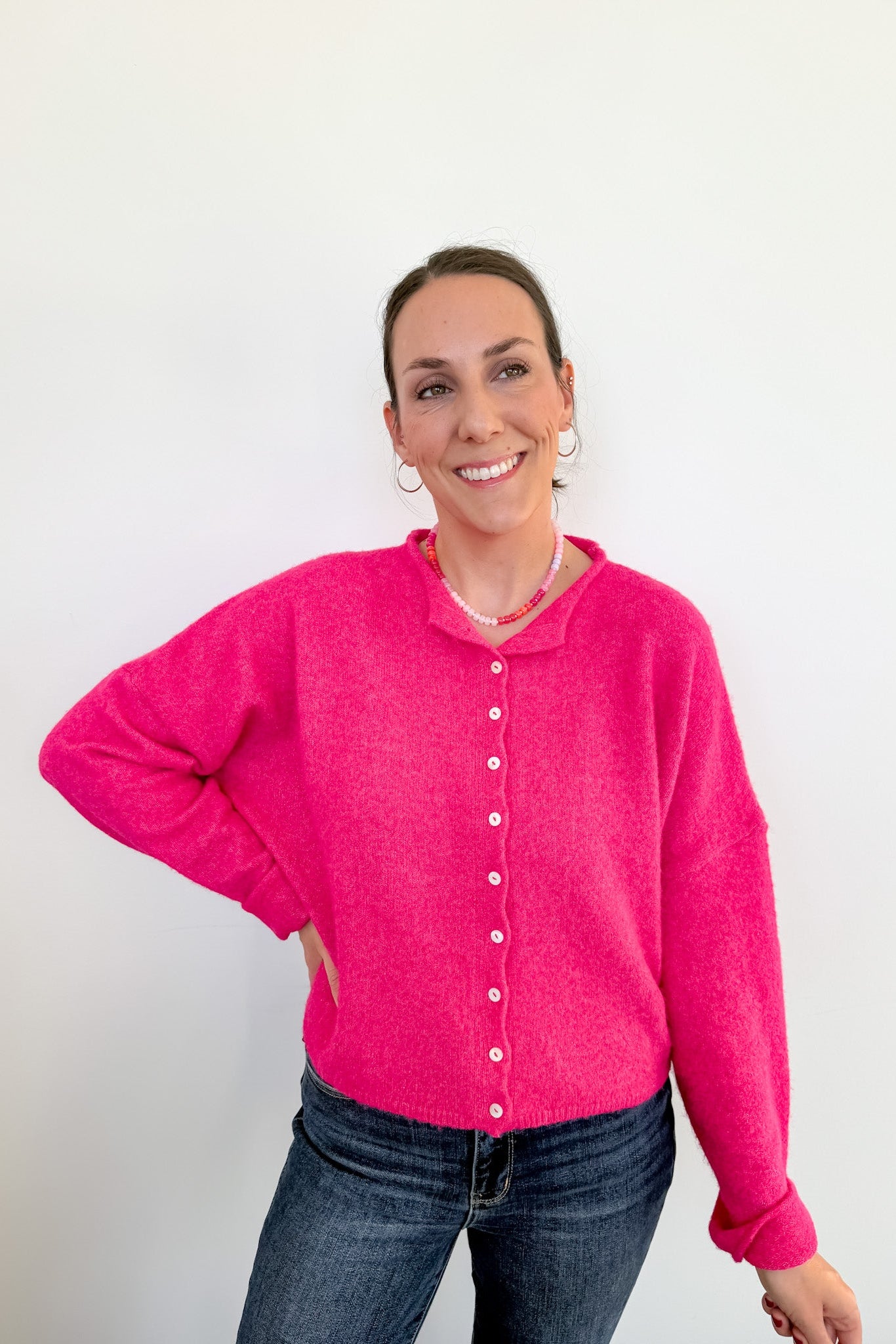 Woman wearing a bright pink cardigan against a white background