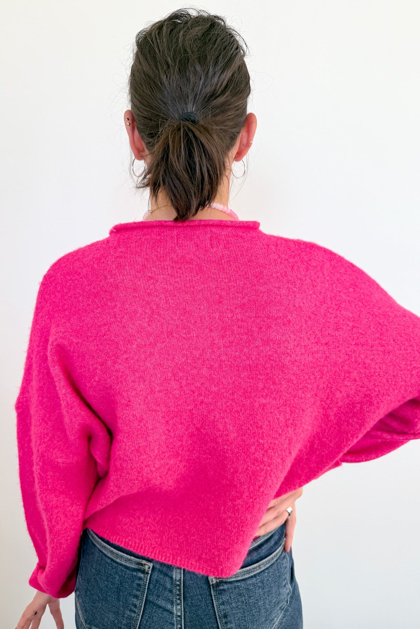 Person wearing a bright pink sweater from behind on a white background