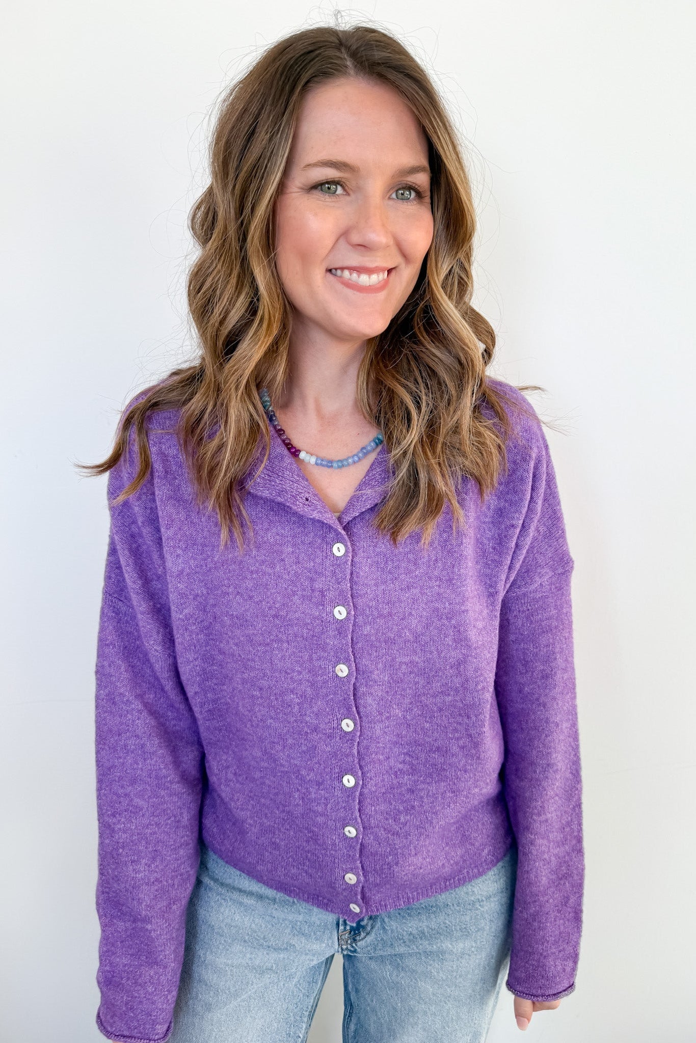 Woman wearing a purple cardigan against a white background