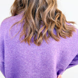 Person wearing a purple sweater with a plain background