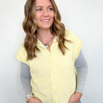 Woman wearing a light yellow vest over a gray shirt with a white background