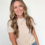 Woman wearing a beige t-shirt and blue jeans against a white background