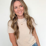 Woman wearing a beige t-shirt and blue jeans against a white background