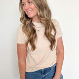 Woman wearing a beige t-shirt and blue jeans against a white background