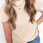 Person wearing a beige top and blue jeans with a plain background