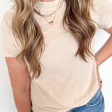 Person wearing a beige top and blue jeans with a plain background