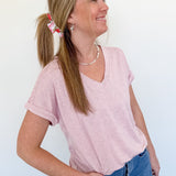 Woman wearing a light pink v neck tee that is short sleeve with jeans