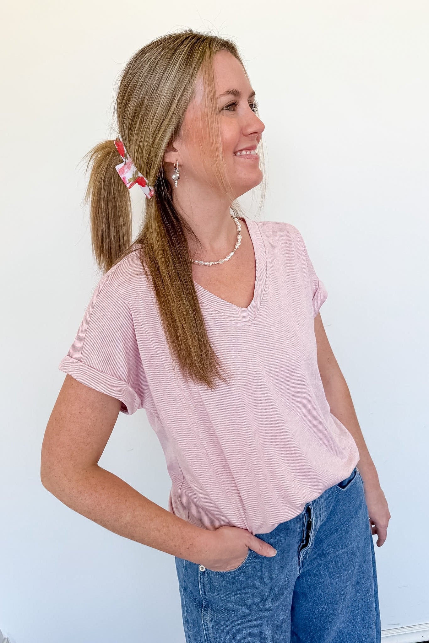 Woman wearing a light pink v neck tee that is short sleeve with jeans