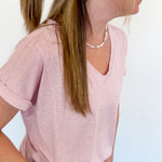 Woman with a floral claw clip in a light pink v neckline tee