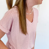 Woman with a floral claw clip in a light pink v neckline tee