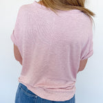 Person wearing a pink shirt and blue jeans against a white background