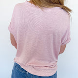 Person wearing a pink shirt and blue jeans against a white background