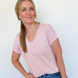 Woman standing with her hand in her pocket in a light pink v neckline tee
