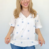 Woven top with light blue embroidered flowers. V neckline. Loose fit. Short sleeve. 