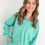 Woman wearing a teal tracksuit against a white background