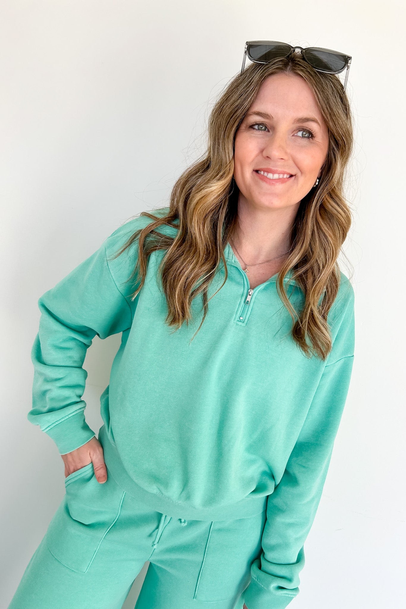 Woman wearing a teal tracksuit against a white background