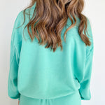 Backside of woman wearing a turquoise sweat set.