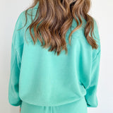 Backside of woman wearing a turquoise sweat set.