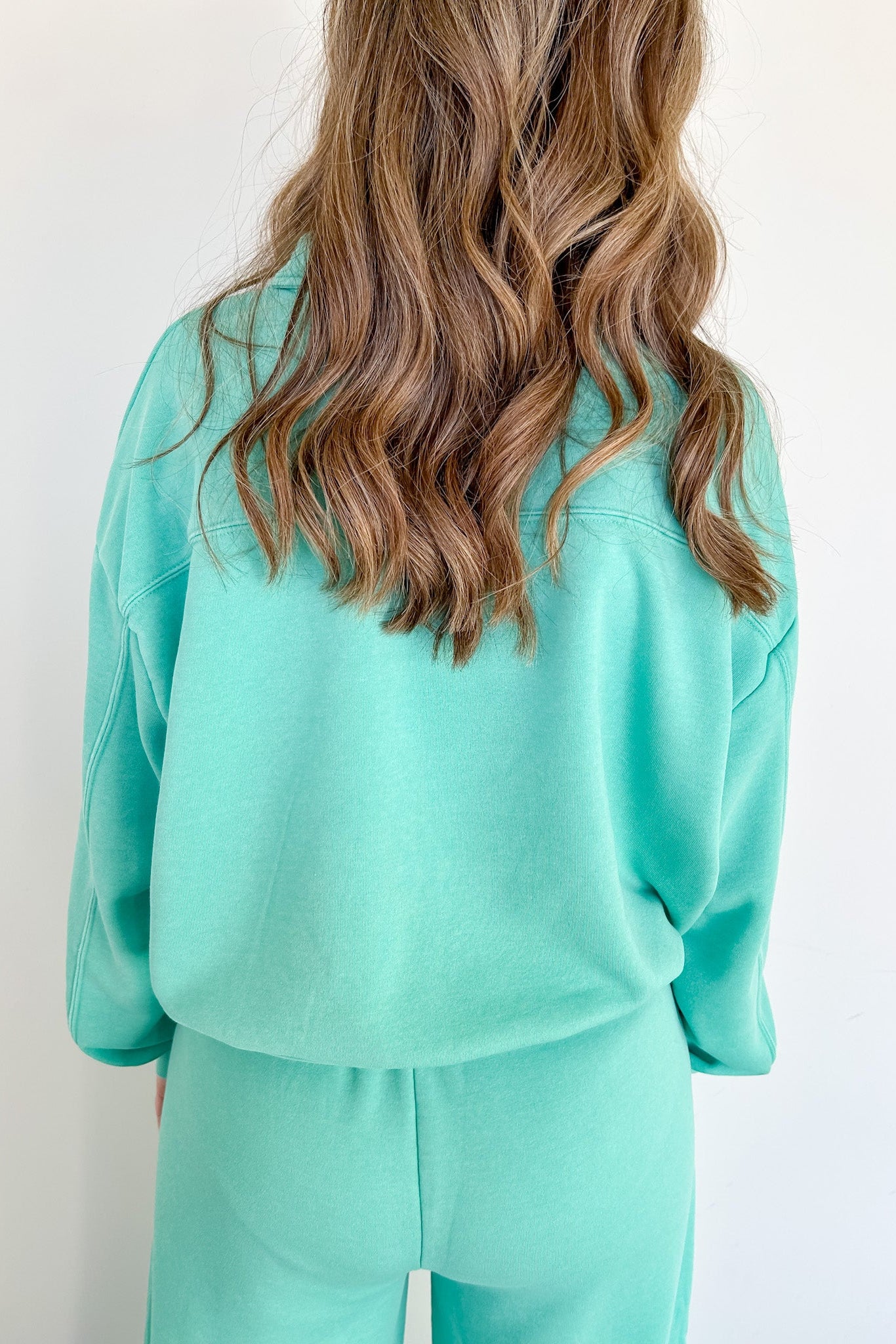 Backside of woman wearing a turquoise sweat set.