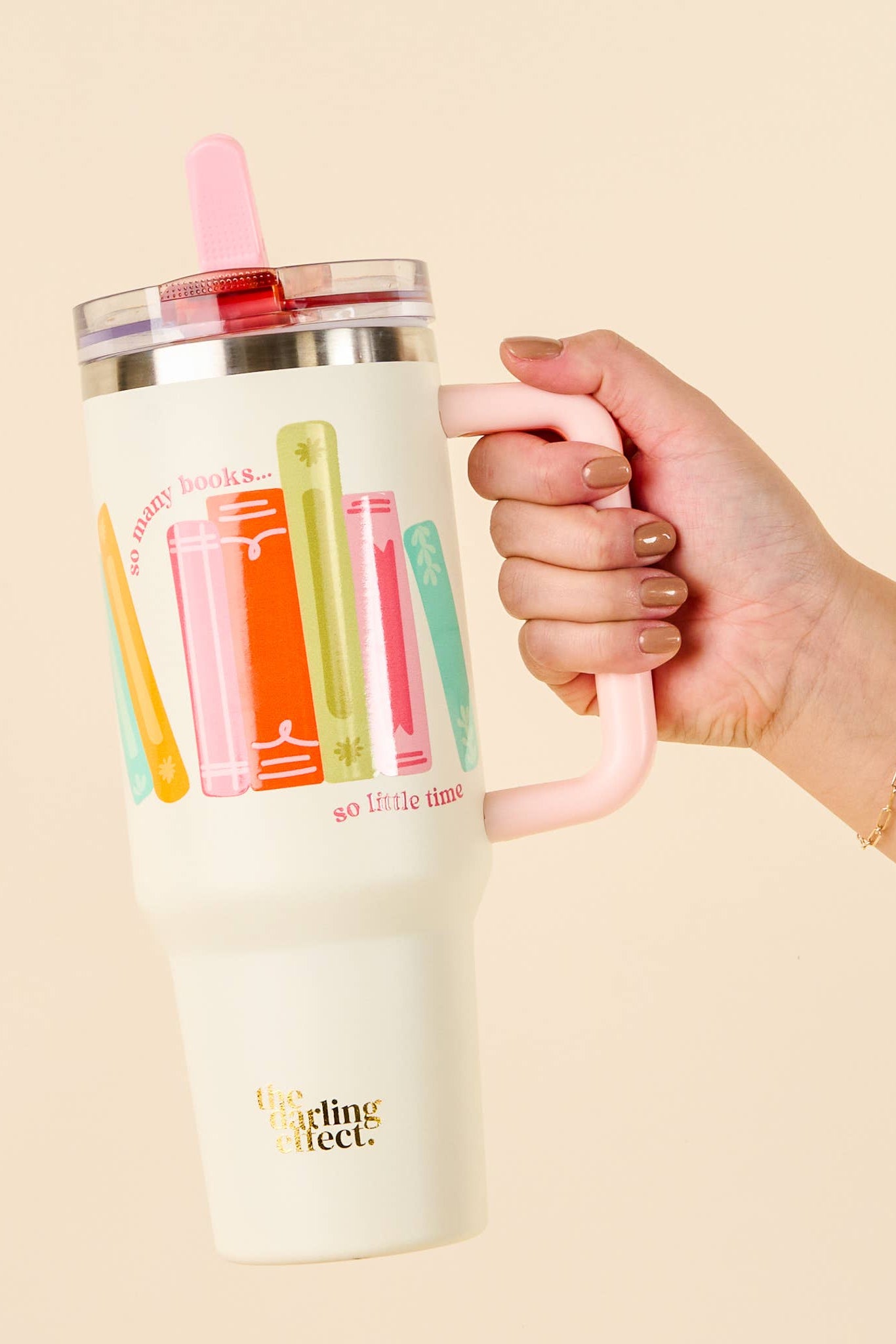 Hand holding a tumbler with colorful designs on a beige background