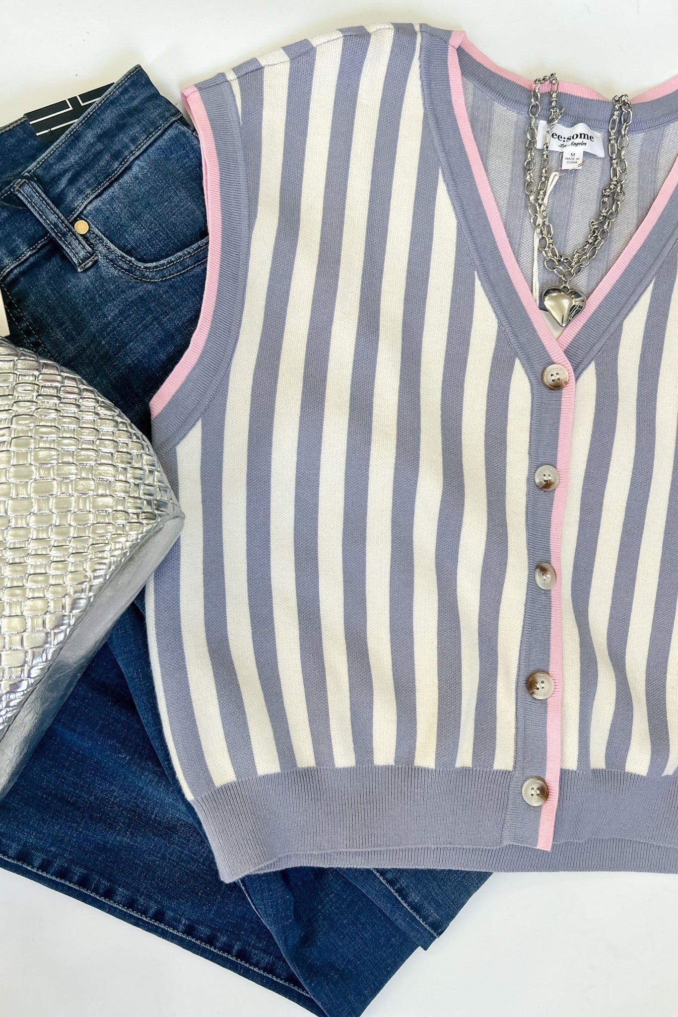 Striped cardigan with jeans and a silver handbag on a white background