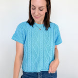 Woman wearing a blue knitted sweater and jeans against a white background