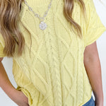 Person wearing a yellow knitted top and blue jeans with a white background