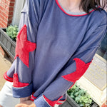 Person wearing a blue sweatshirt with red star designs outdoors.