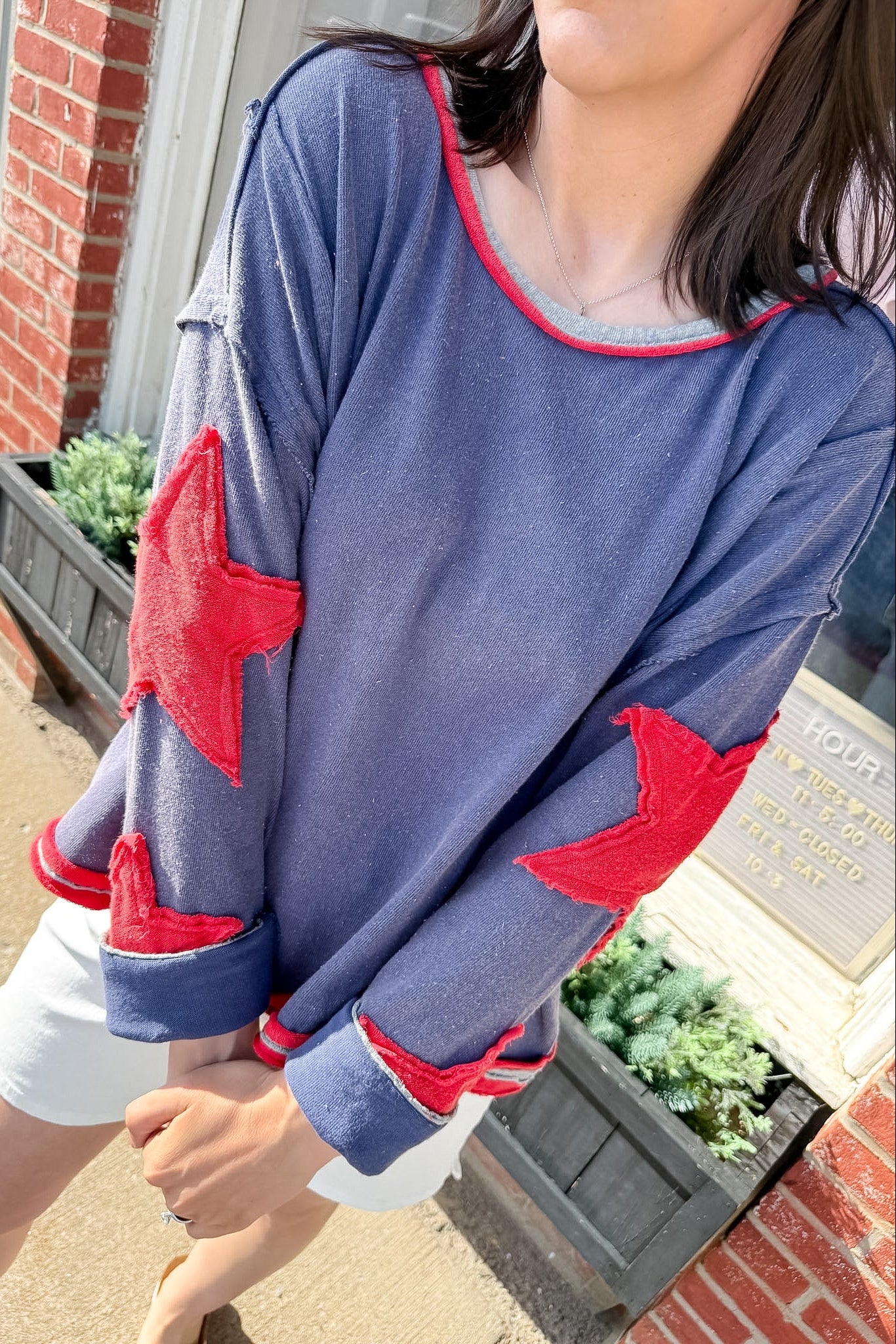 Person wearing a blue sweatshirt with red star designs outdoors.