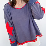 Person wearing a gray sweatshirt with red elbow patches and white shorts against a white background