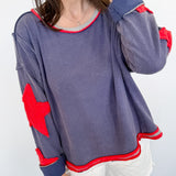 Person wearing a gray sweatshirt with red elbow patches and white shorts against a white background