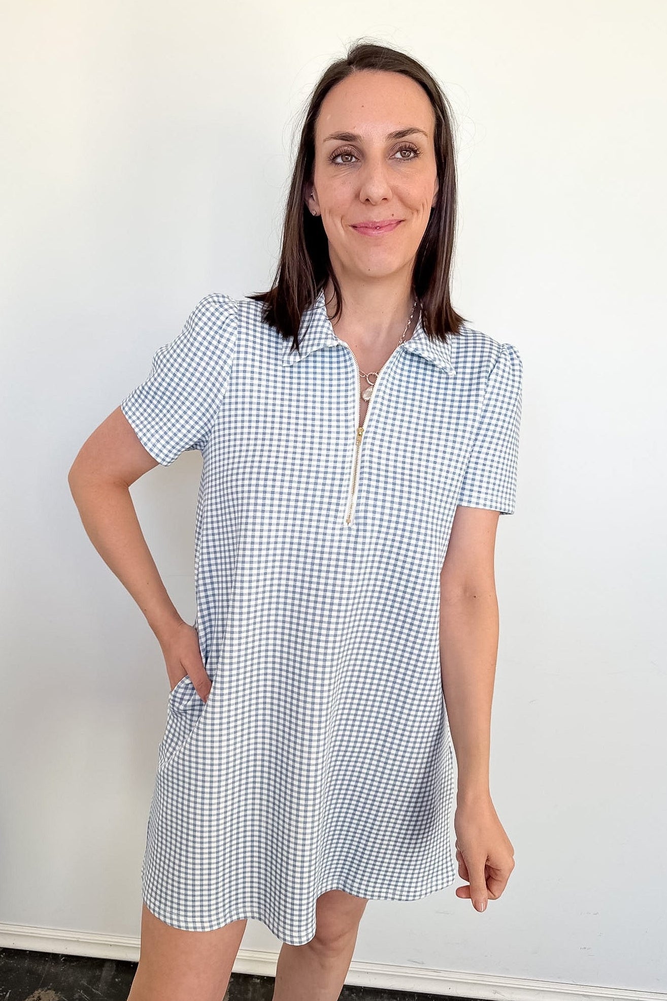 Woman wearing a blue and white checkered dress against a plain background