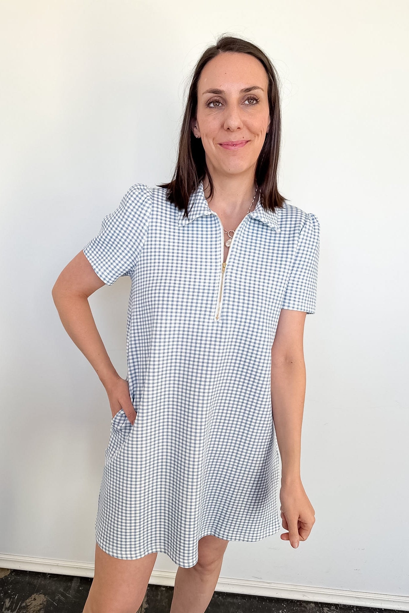 Woman wearing a blue and white checkered dress against a plain background