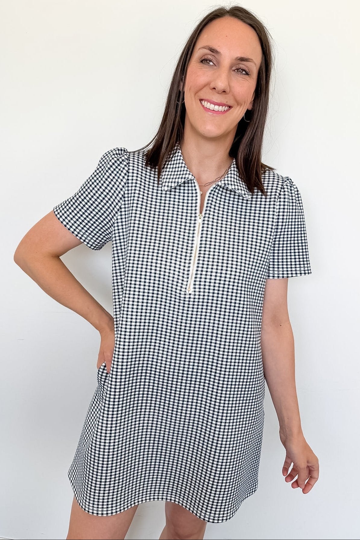 Woman wearing a black and white checkered dress against a plain background