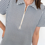 Person wearing a black and white checkered dress with a zipper detail on a white background