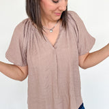 Mauve colored top with a v neckline and puff sleeve detailing. Regular fitting top. Blouse style.