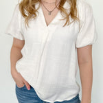 White colored top with a v neckline and puff sleeve detailing. Regular fitting top. Blouse style.