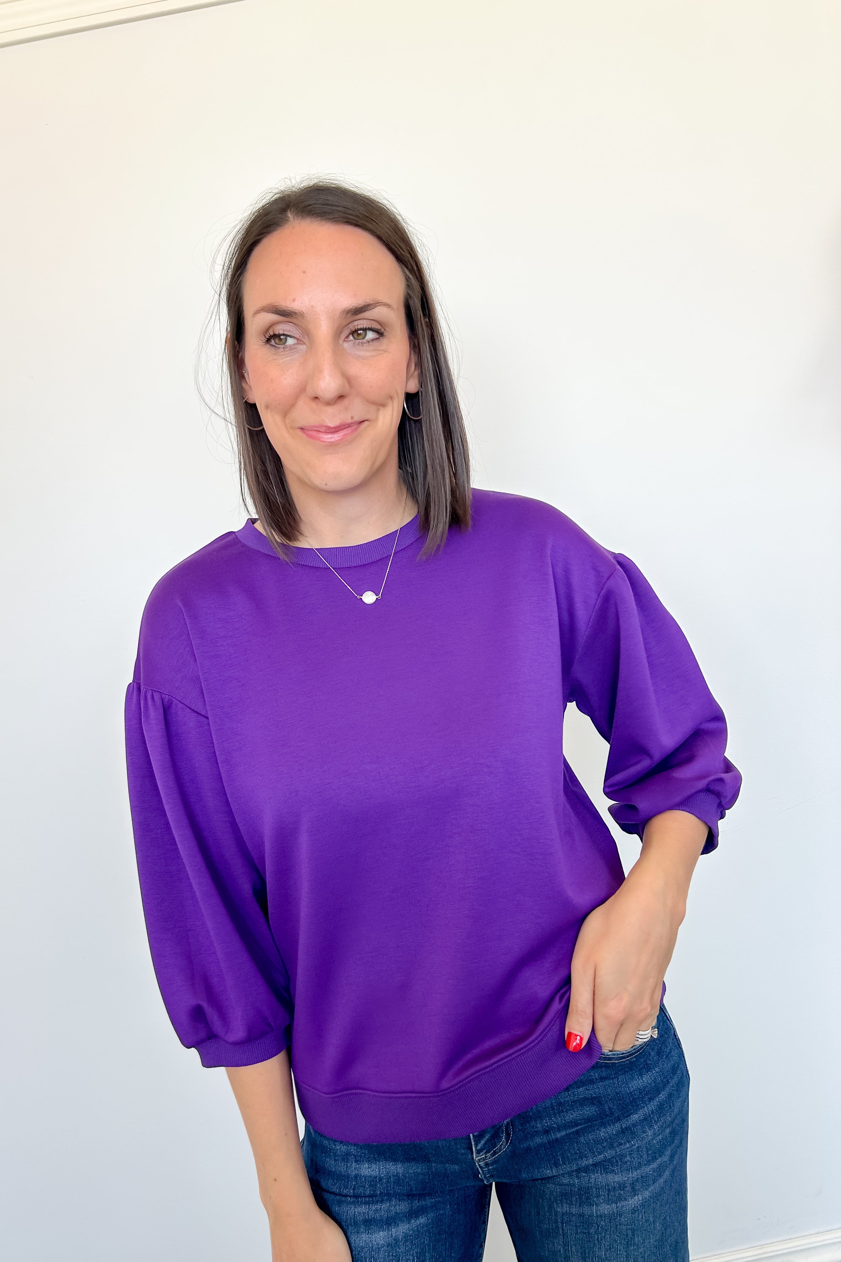 Woman wearing a purple sweatshirt against a white background