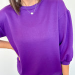 Person wearing a purple top and blue jeans against a white background