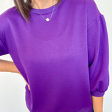 Person wearing a purple top and blue jeans against a white background