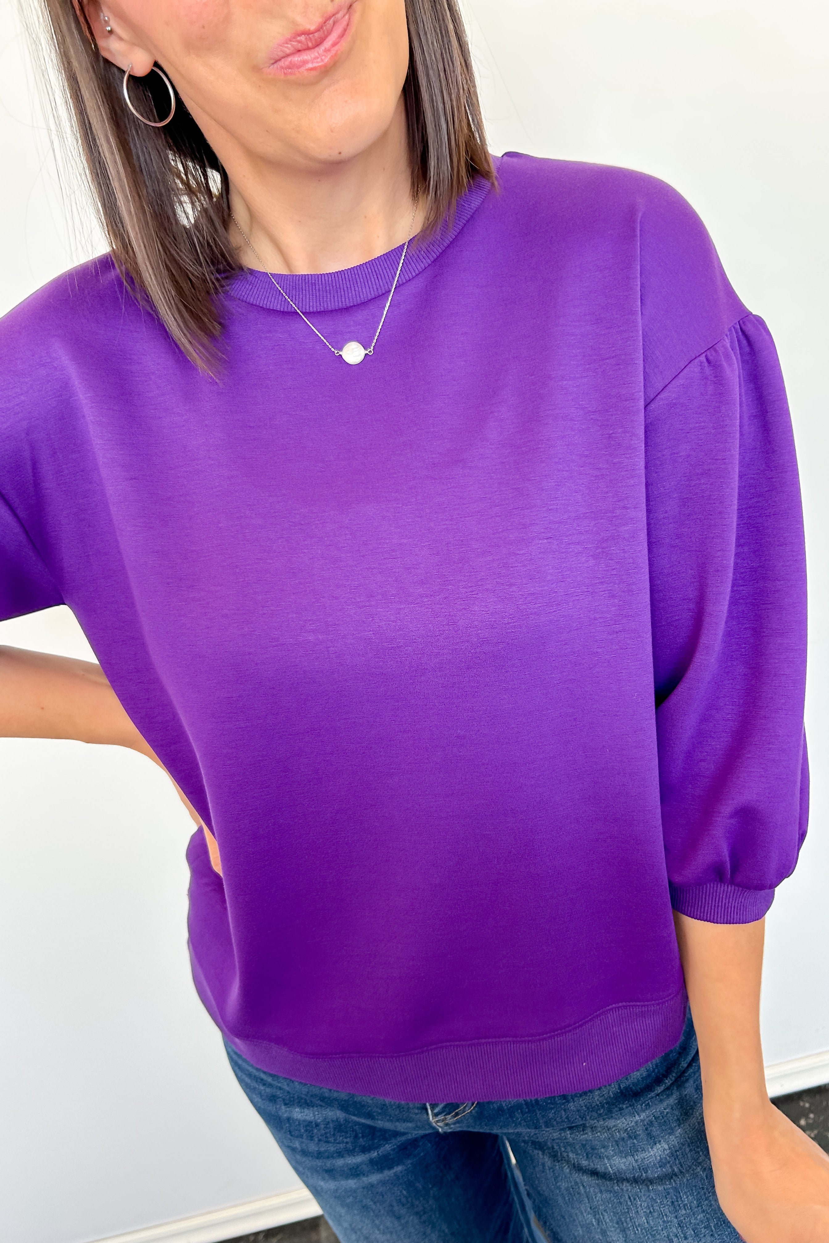 Person wearing a purple top and blue jeans against a white background