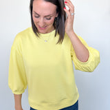 Woman wearing a yellow blouse and blue jeans against a white background