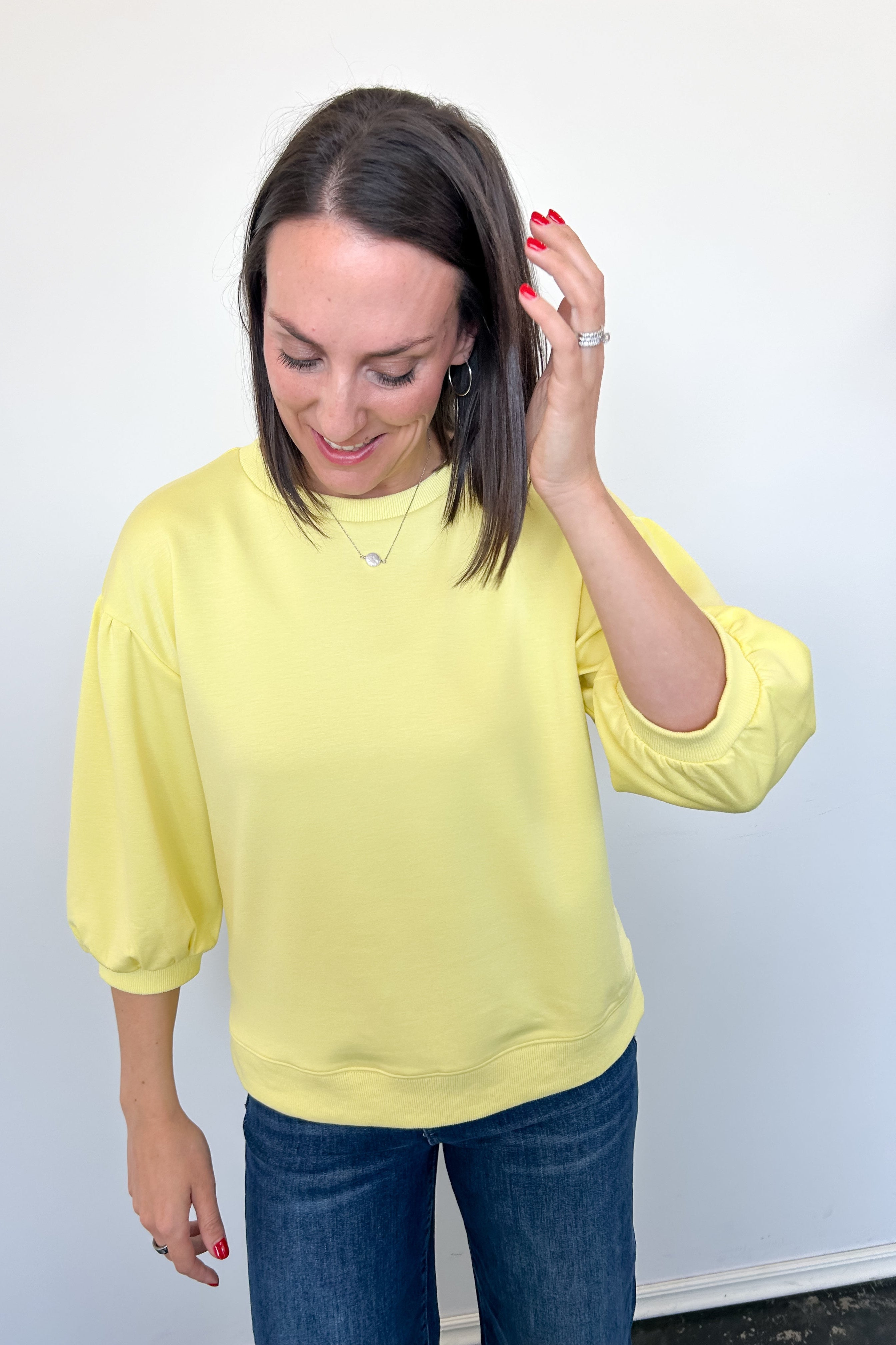 Woman wearing a yellow blouse and blue jeans against a white background