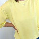 Person wearing a yellow top and blue jeans against a plain background