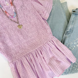 Purple dress with denim jeans and sunglasses on a white background