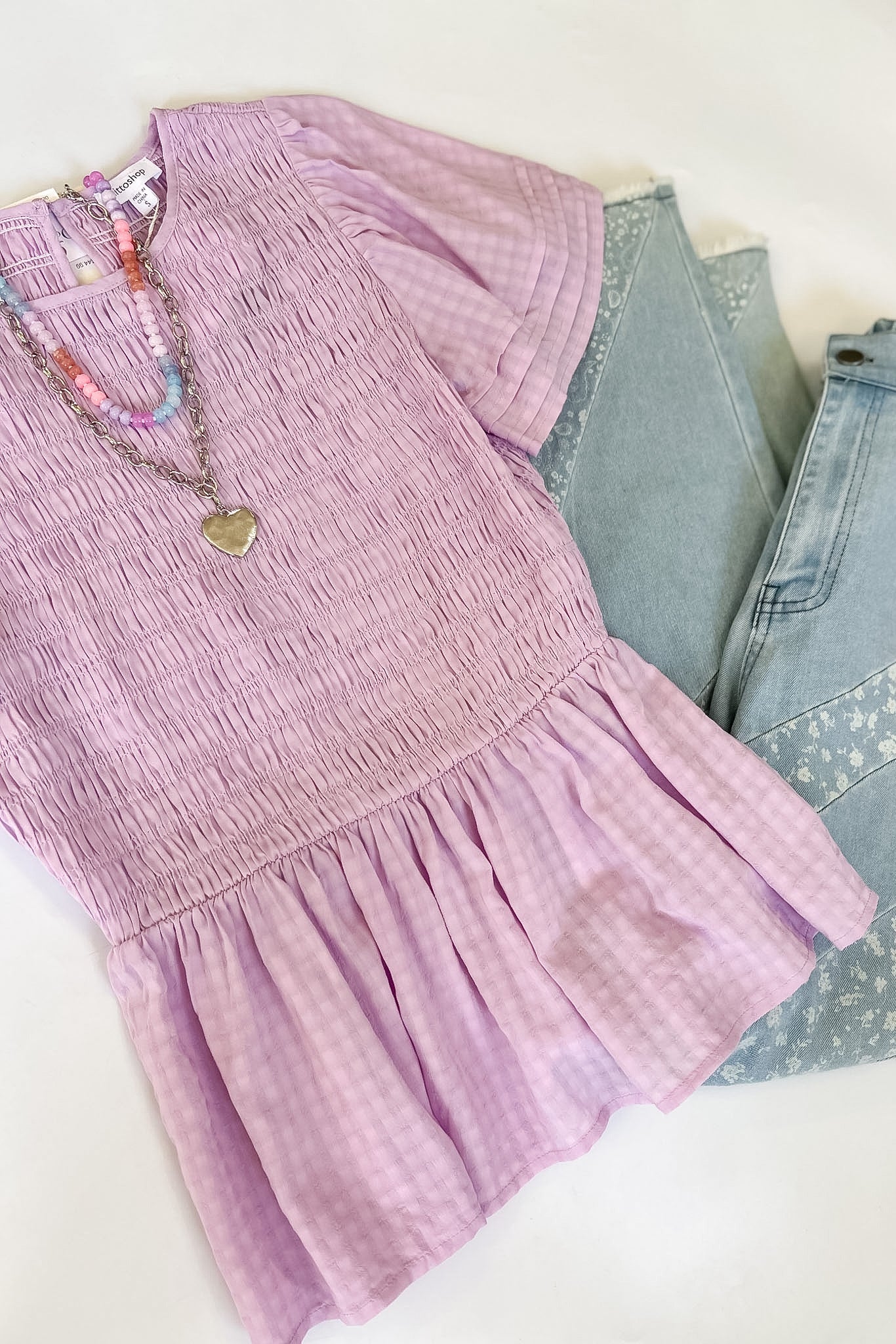 Purple dress with denim jeans and sunglasses on a white background